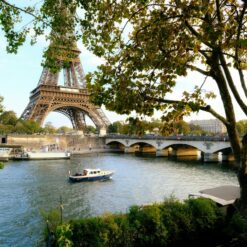 Captivating view of Eiffel Tower over Seine River with lush trees in Paris, France.